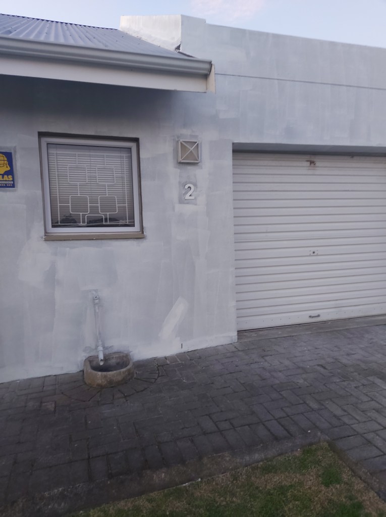 house covered in white paint can see garage kitchen window and drain